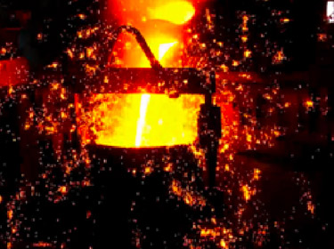 鋳造工場の電気炉で溶かした溶湯（溶けた鉄）を取鍋に移している様子。火花が散って迫力がある。